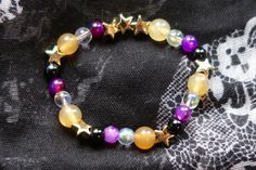 Nonbinary pride flag star beaded gemstone bracelet. The beads are the nonbinary flag colors (yellow, white, purple, black) and gold stars. ♥ Bracelet Size: - To find the size that fits you best, you can measure the circumference around your wrist; for a comfort/loose fit, add 2cm to that measurement ♥ Handcrafted With: ✔ High-quality gemstone beads ✔ Durable stretchy cord Thank you for visiting! If you have any questions, feel free to contact me!  Instagram: @FrogsMakingToast Nonbinary Jewelry, Agender Bracelet, Nonbinary Bracelet, Purple Star-shaped Bracelet For Gift, Subtle Nonbinary, Purple Star-shaped Bracelets For Gifts, Lgbtq Gifts, Purple Star-shaped Beaded Jewelry, Lesbian Pride Bead Bracelet