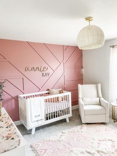 a baby's room with pink walls and white furniture