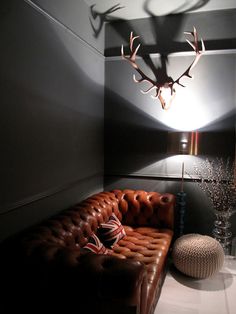 a room with a couch, lamp and deer head on the wall