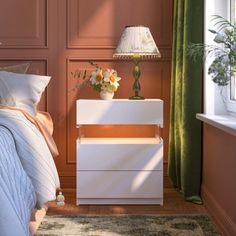 a white nightstand sitting next to a bed on top of a wooden floor near a window