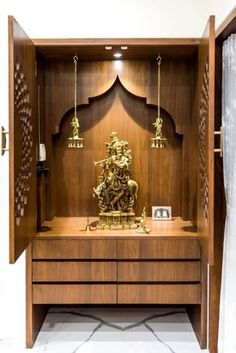 a wooden cabinet with a statue in the middle and other items on top of it