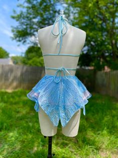 a mannequin with a blue dress on it's back and some green grass in the background