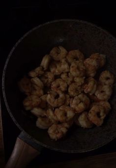 shrimp being cooked in a frying pan on top of a wooden stove burner