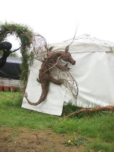 an animal made out of vines sitting on top of a white sheet in the grass