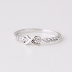 a white gold ring with diamonds in the middle and an intertwined band on top