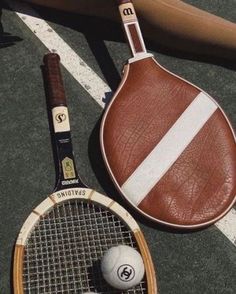 a tennis racket and ball are on the ground next to a bat that is leaning against it