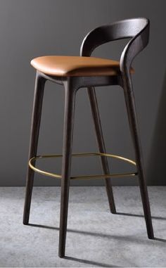 a wooden bar stool with leather seat and backrests in front of a gray wall