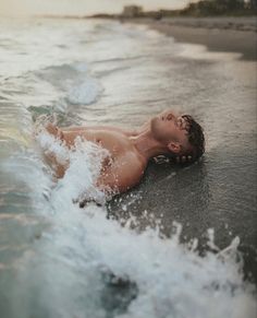 a man laying on top of a body of water next to the ocean with waves