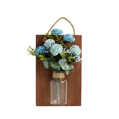 a mason jar filled with blue flowers sitting on top of a wooden plaque mounted to a wall