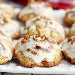 there are many cookies with icing and nuts on the top one is sitting on a white plate