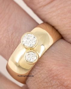 a close up of a person's hand wearing a gold ring with two diamonds