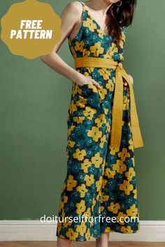 a woman standing in front of a green wall wearing a dress with yellow flowers on it