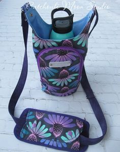 a purple and blue flowered handbag with a water bottle in it on the ground