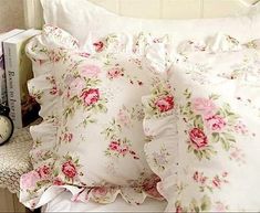 a white bed topped with lots of pink flowers next to a night stand and alarm clock