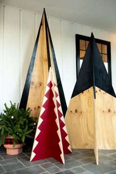 three wooden christmas trees sitting next to each other on a tile floor in front of a white wall