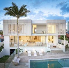 a large white house with a pool in front of it and palm trees on the other side