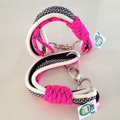 two pink and black dog leashes with white trimmings on each side, one has an id tag attached to it