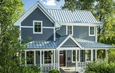 a blue house with white trim on the front and side of it, surrounded by trees