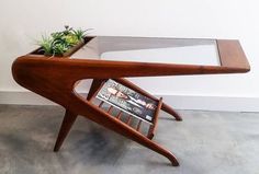 a wooden table with a magazine rack and planter on top