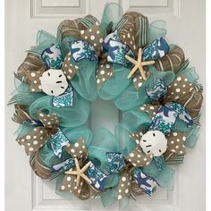 a wreath with starfishs and sea shells on it is hanging on the front door