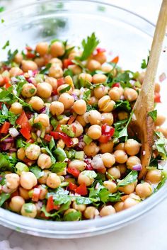 a salad with chickpeas, lettuce and carrots in a glass bowl