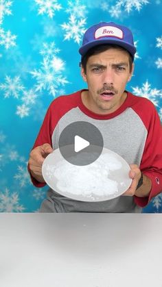 a man holding a plate with snow flakes on the wall behind him and making a funny face