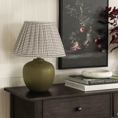 a green vase sitting on top of a wooden table next to a lamp and books