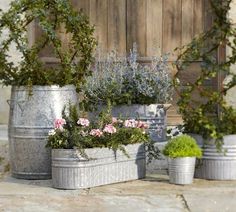 three metal buckets filled with flowers and greenery