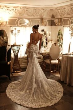 a woman standing in front of a mirror wearing a wedding dress with an open back