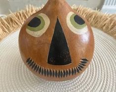 a brown vase with eyes painted on it sitting on a white tablecloth covered surface