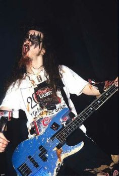 a man with long hair and black makeup holding a blue guitar in front of his face