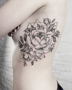 a black and white photo of a woman's stomach with a rose tattoo on it