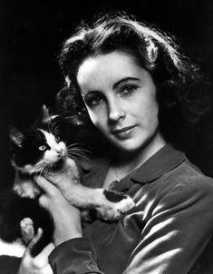 an old black and white photo of a young woman holding a cat in her arms