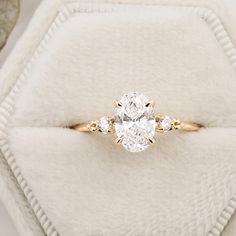 an oval diamond ring with three smaller round diamonds on the band, set in yellow gold