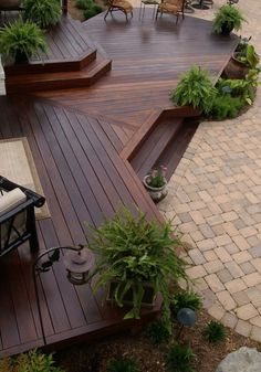 a deck with steps leading up to an outdoor living room and dining area in the background