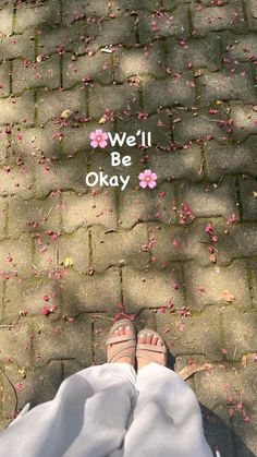 someone is standing on the sidewalk with their feet up and there are pink flowers all over them