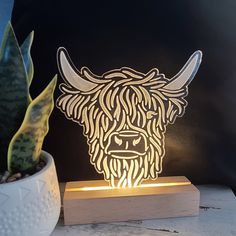 a light up cow head sitting on top of a table next to a potted plant