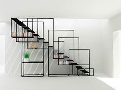 a set of black shelves with books and vases on them in an empty room