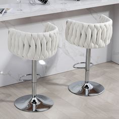 two white bar stools sitting on top of a wooden floor