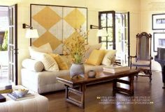 a living room filled with white furniture and lots of yellow pillows on the couches