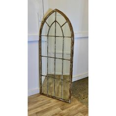 an old arched window is sitting on the floor in front of a wooden flooring