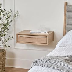 a bedroom with a bed, nightstand and potted plant on the side table next to it