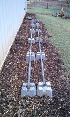 the train tracks are lined up along the side of the fenced in area with mulch on the ground