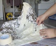 someone is making a cake with tin foil on top of the paper and wrapping around it