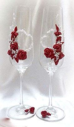 two wine glasses decorated with red roses and pearls