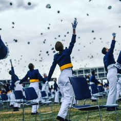 a group of people in blue and white uniforms are throwing graduation caps into the air