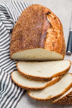 a loaf of bread sliced and sitting on top of a striped towel next to a knife