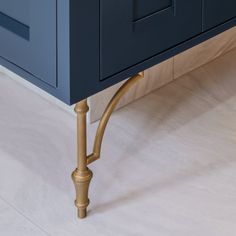 a blue cabinet with brass handles on the top and bottom, against a white floor