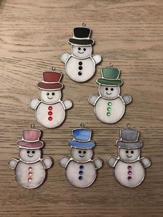 six snowmen wearing hats and standing on top of a wooden table