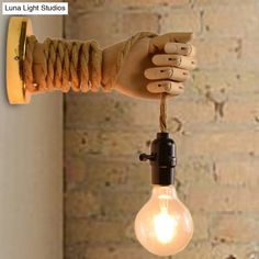 a light bulb being held by a hand with a string attached to it and some lights on the wall